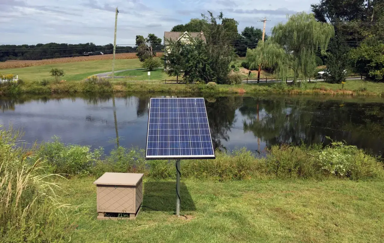 Panneau solaire près d'un étang, solution pour comment oxygéner l'eau sans pompe. Un boîtier beige est à côté.